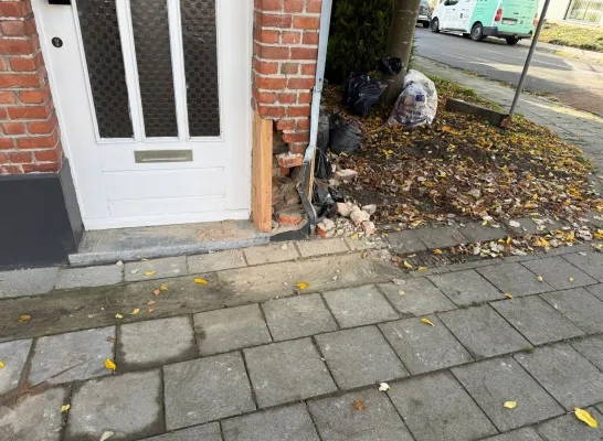 Auto rijdt tegen hoek woning, bewoonster in shock