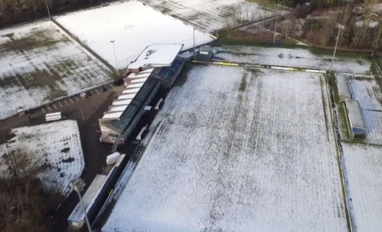 Dronebeeld van besneeuwd voetbalveld in Heist.